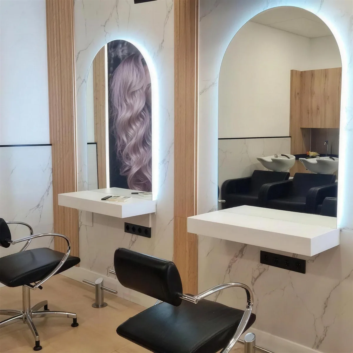El salón de MB Connection Style: mármol blanco, espejos en arco con luz y sillones negros